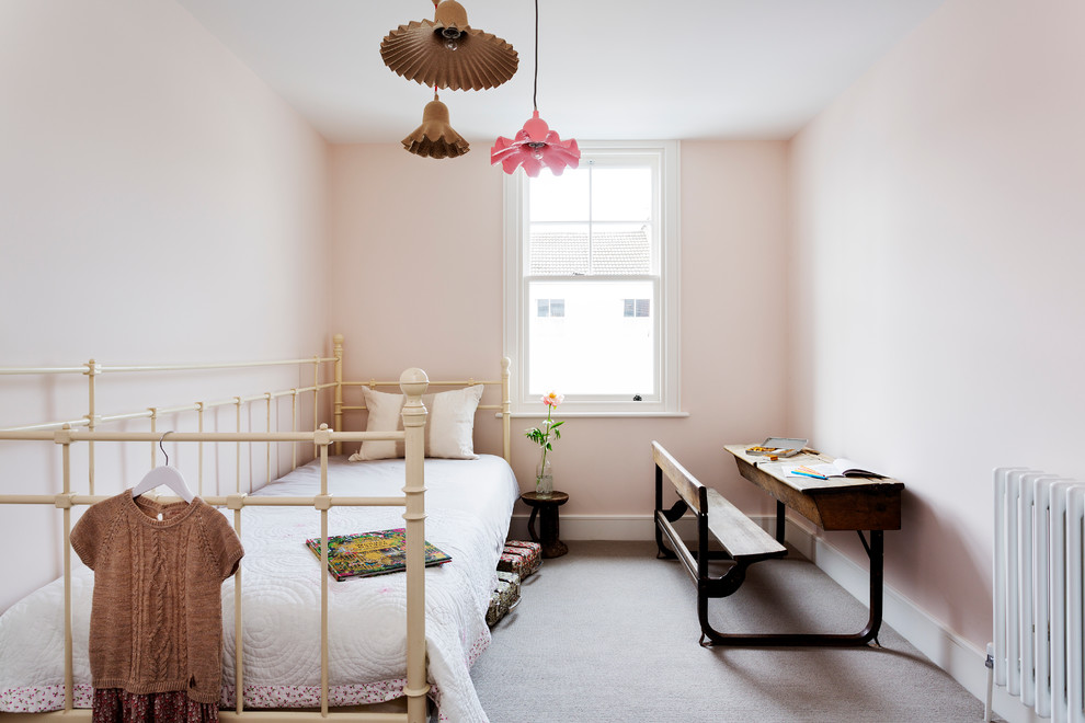This is an example of a mid-sized contemporary kids' bedroom for kids 4-10 years old and girls in London with pink walls and carpet.