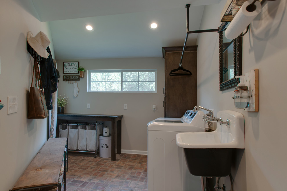 Design ideas for a small country utility room in Nashville with a farmhouse sink, shaker cabinets, brown cabinets, granite benchtops, grey walls, brick floors, a side-by-side washer and dryer, multi-coloured floor and black benchtop.