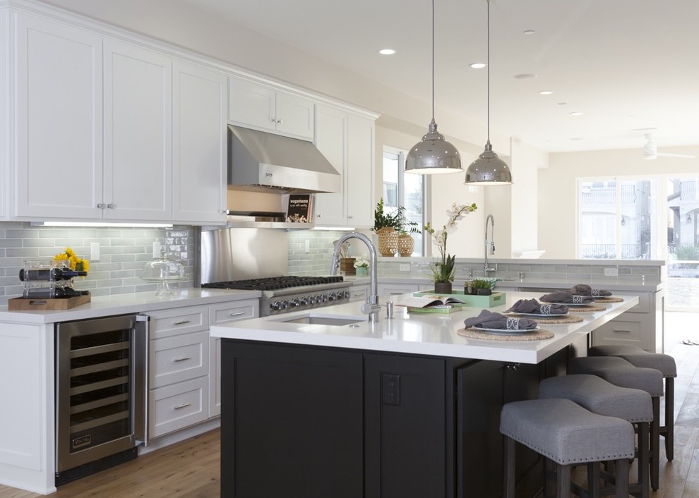 Inspiration for a mid-sized transitional l-shaped kitchen in Los Angeles with an undermount sink, shaker cabinets, white cabinets, quartz benchtops, grey splashback, subway tile splashback, stainless steel appliances, medium hardwood floors and with island.