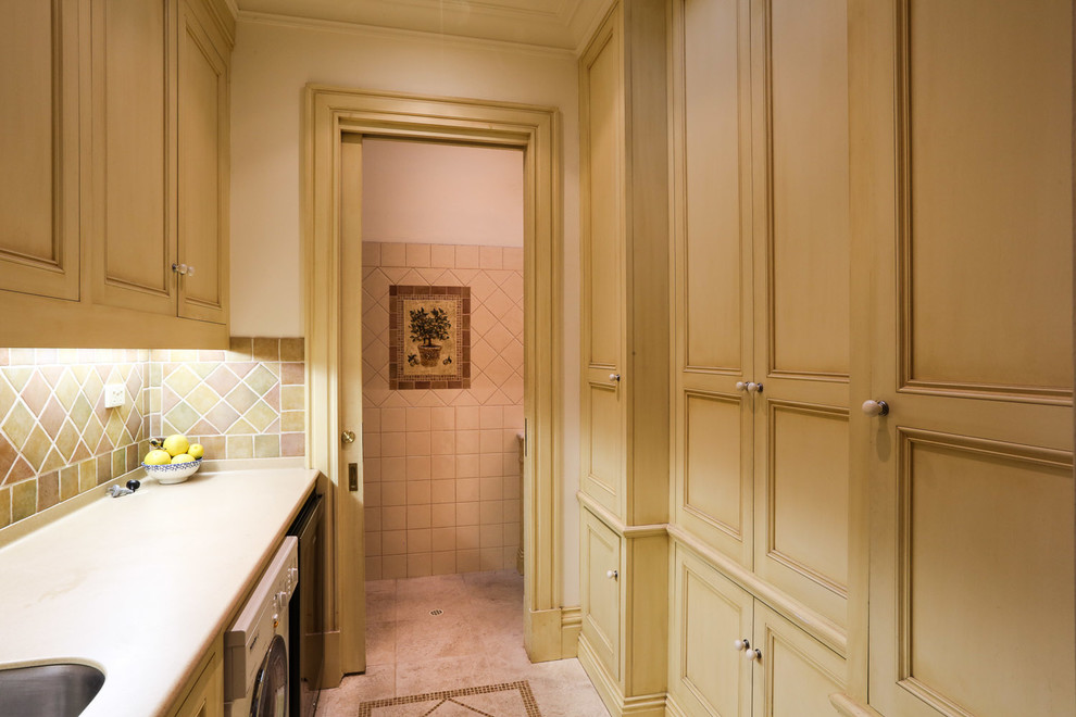 Photo of a small traditional galley utility room in Adelaide with solid surface benchtops, beige walls, marble floors, recessed-panel cabinets and light wood cabinets.
