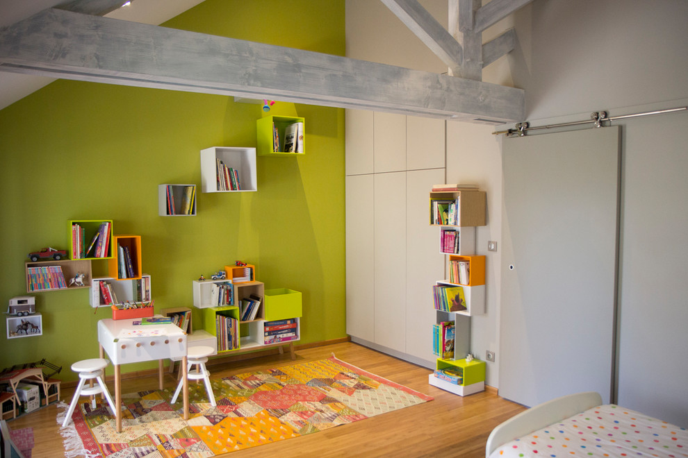Large modern gender-neutral kids' playroom in Nantes with green walls, light hardwood floors and brown floor for kids 4-10 years old.