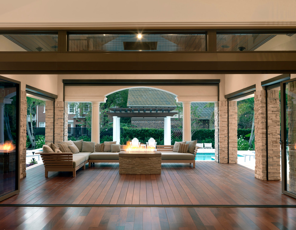 Inspiration for a large contemporary backyard and ground level deck in Tampa with a fire feature and a roof extension.