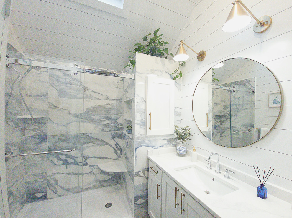Maritim inredning av ett mellanstort vit vitt en-suite badrum, med skåp i shakerstil, vita skåp, en dusch i en alkov, vit kakel, keramikplattor, vita väggar, ett undermonterad handfat, blått golv, dusch med skjutdörr och bänkskiva i kvarts