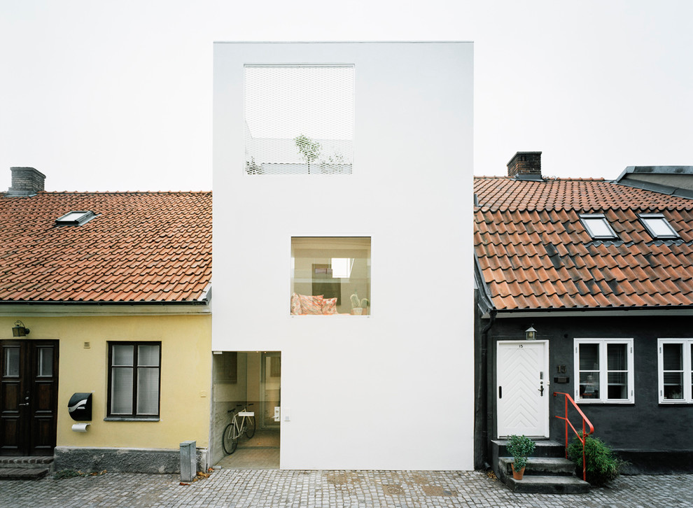 Design ideas for a large contemporary three-storey white townhouse exterior in Malmo with a flat roof and stone veneer.