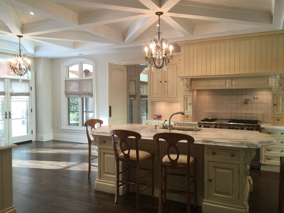 Large transitional l-shaped dark wood floor open concept kitchen photo in Toronto with a double-bowl sink, raised-panel cabinets, beige cabinets, white backsplash, stainless steel appliances and an island