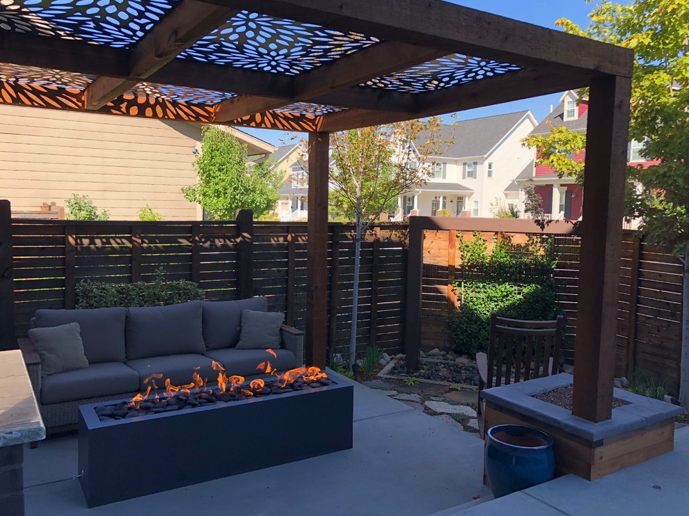 Design ideas for a small modern backyard patio in Denver with a fire feature, concrete slab and a pergola.
