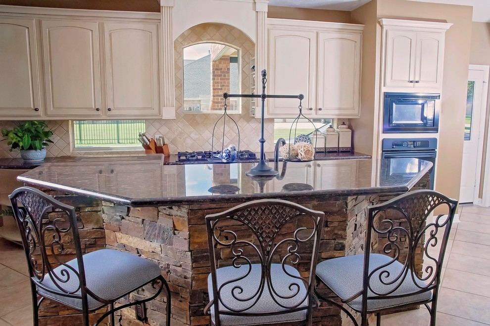 Inspiration for a mid-sized traditional l-shaped separate kitchen in Houston with an undermount sink, raised-panel cabinets, white cabinets, granite benchtops, beige splashback, travertine splashback, stainless steel appliances, travertine floors, with island, beige floor and beige benchtop.