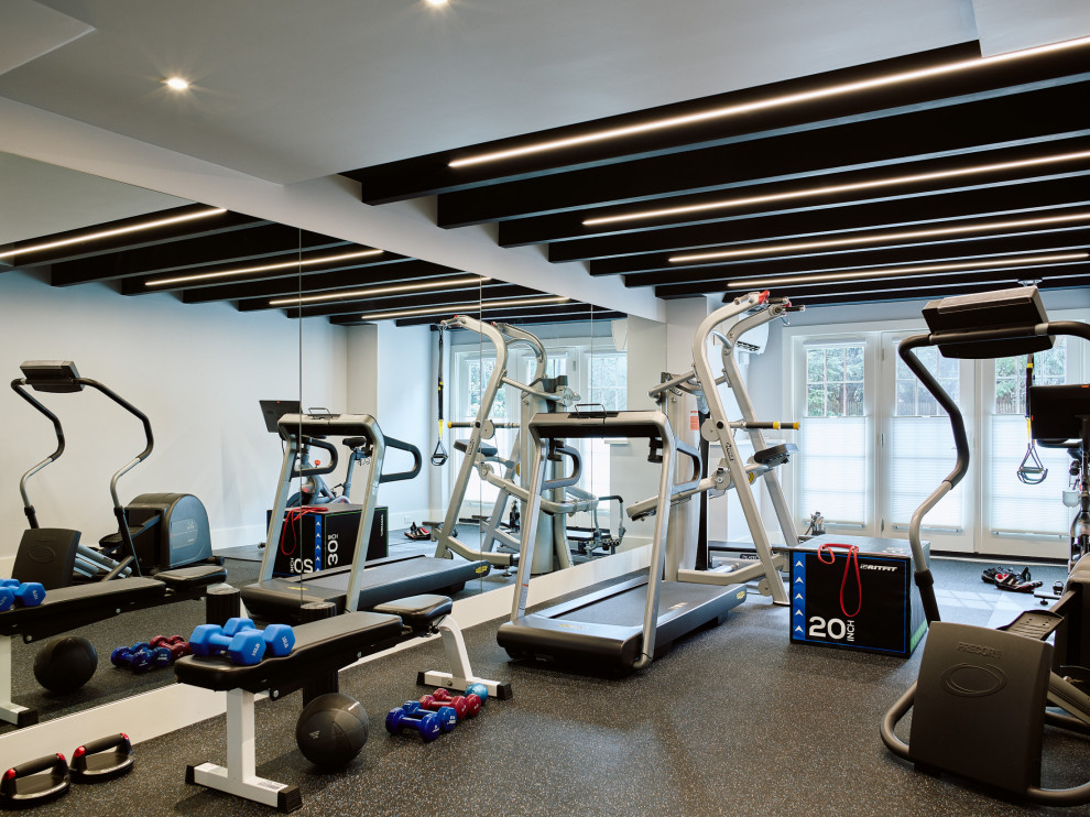 Imagen de sala de pesas contemporánea grande con paredes grises, suelo multicolor y vigas vistas