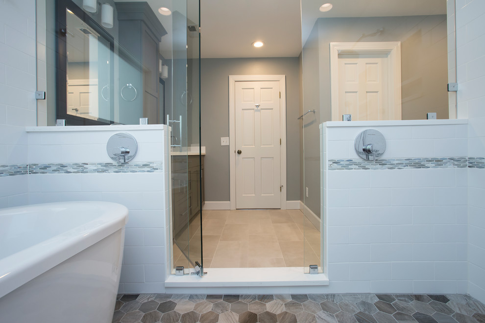 This is an example of a large transitional master wet room bathroom in Raleigh with shaker cabinets, grey cabinets, a freestanding tub, a two-piece toilet, white tile, ceramic tile, blue walls, porcelain floors, an undermount sink, engineered quartz benchtops, grey floor, a hinged shower door and white benchtops.