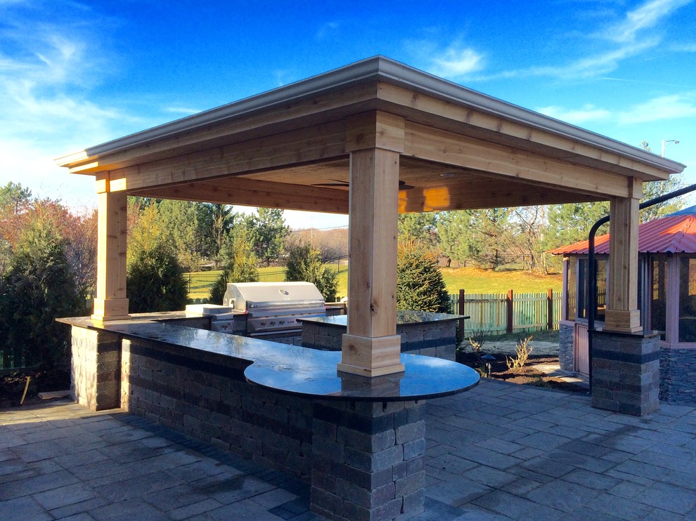Inspiration for a mid-sized country backyard patio in Chicago with an outdoor kitchen, natural stone pavers and a gazebo/cabana.