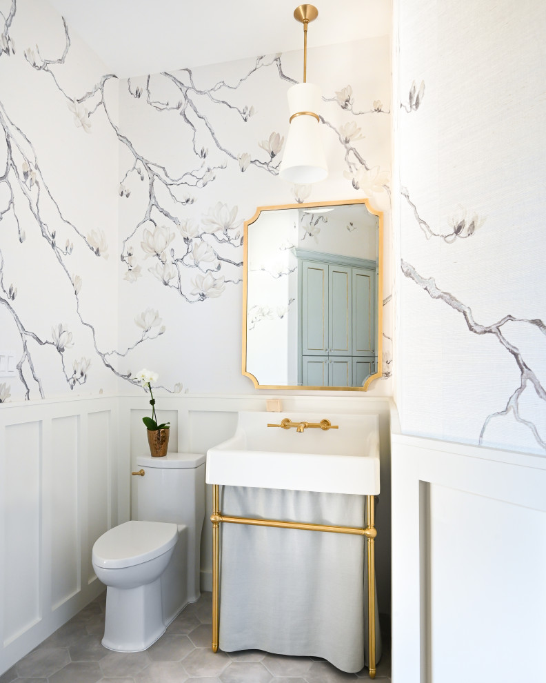 Photo of a small cloakroom with freestanding cabinets, white cabinets, a one-piece toilet, white walls, porcelain flooring, a console sink, grey floors, a freestanding vanity unit and wallpapered walls.