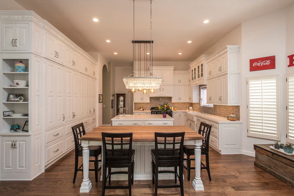 Eat-in kitchen - mid-sized traditional u-shaped medium tone wood floor and brown floor eat-in kitchen idea in Phoenix with a farmhouse sink, raised-panel cabinets, white cabinets, quartz countertops, beige backsplash, paneled appliances and two islands