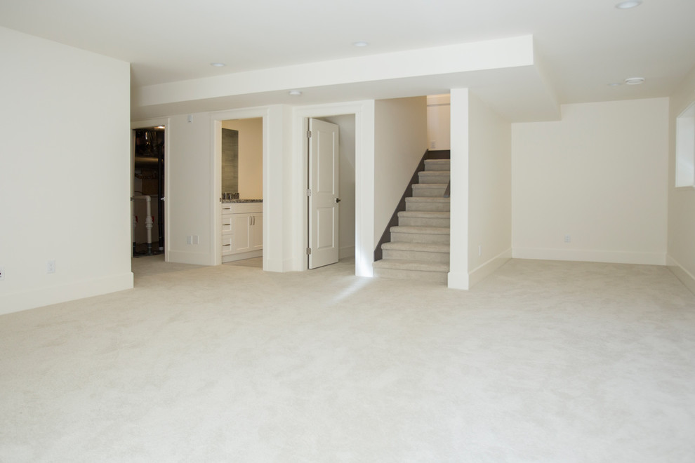 Large modern fully buried basement in Vancouver with white walls, carpet and no fireplace.