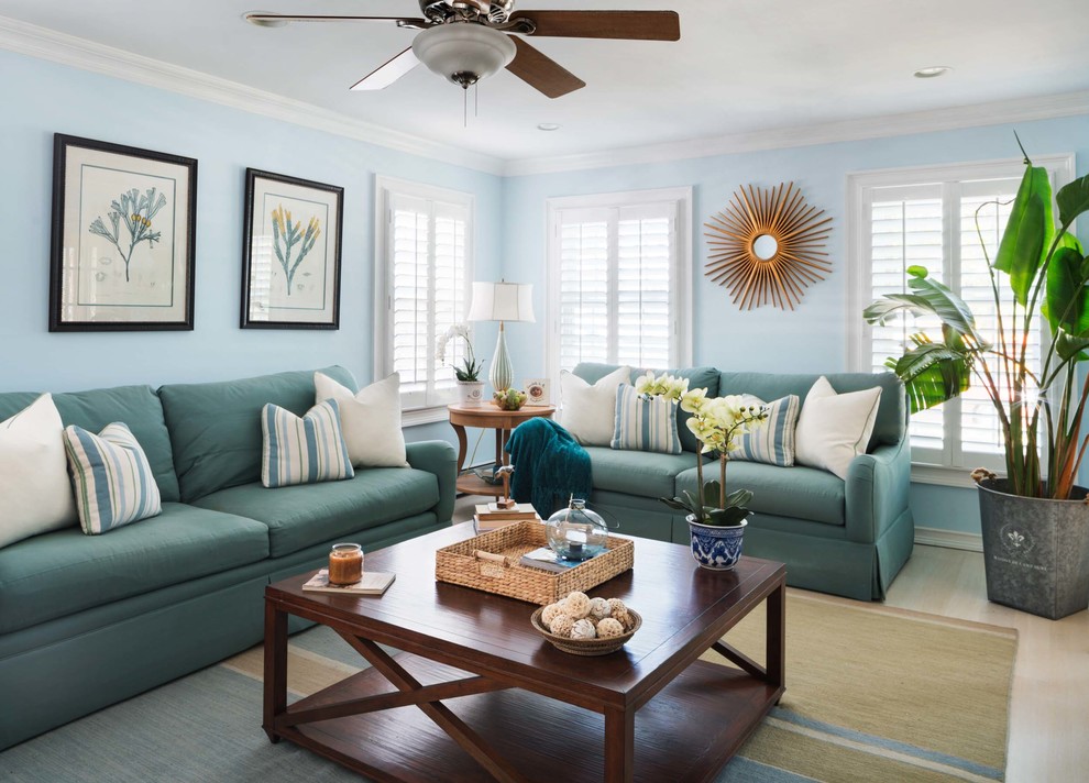 Inspiration for a mid-sized beach style enclosed family room in New York with blue walls, no fireplace, a wall-mounted tv and light hardwood floors.