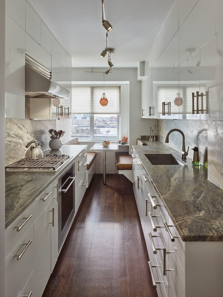 Small trendy galley dark wood floor enclosed kitchen photo in New York with no island, an undermount sink, flat-panel cabinets, white cabinets, quartzite countertops, stone slab backsplash and stainless steel appliances