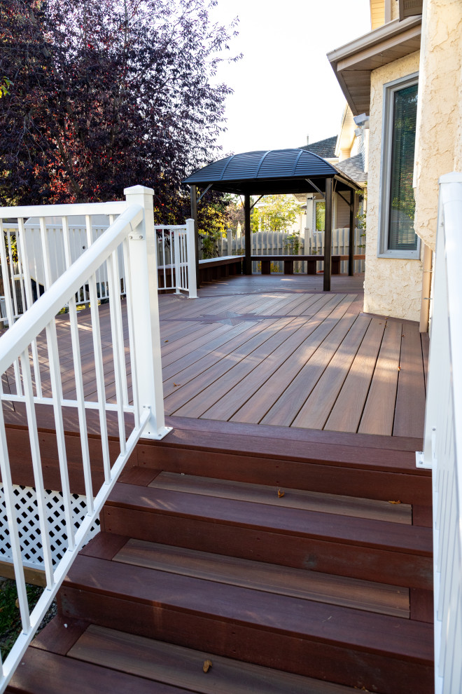 Design ideas for an expansive modern backyard and ground level deck in Edmonton with no cover and metal railing.