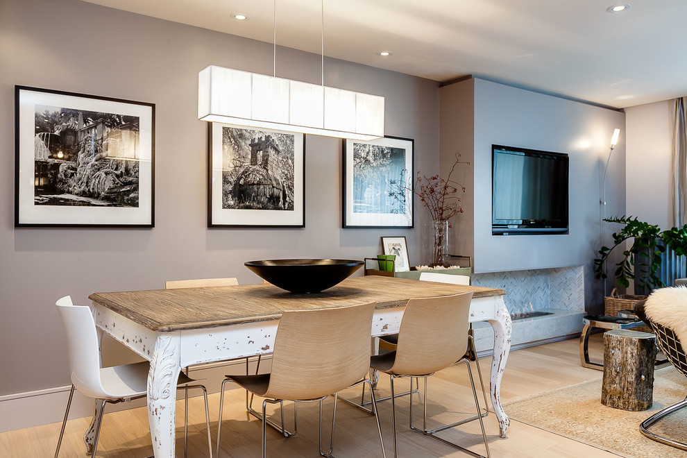 This is an example of a mid-sized contemporary open plan dining in Toronto with grey walls, light hardwood floors, a ribbon fireplace and a tile fireplace surround.
