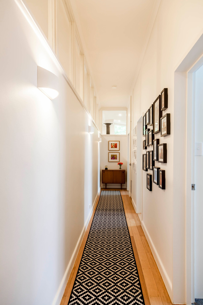 This is an example of a mid-sized midcentury hallway in Melbourne with white walls, medium hardwood floors and beige floor.