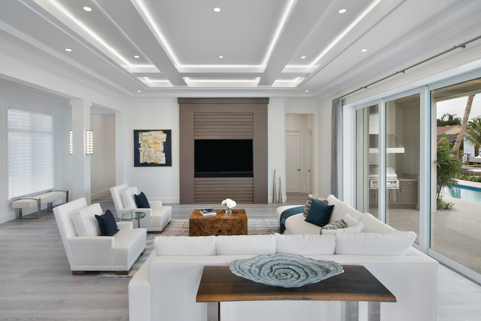 Contemporary living room in Miami with white walls, a wall-mounted tv and grey floor.