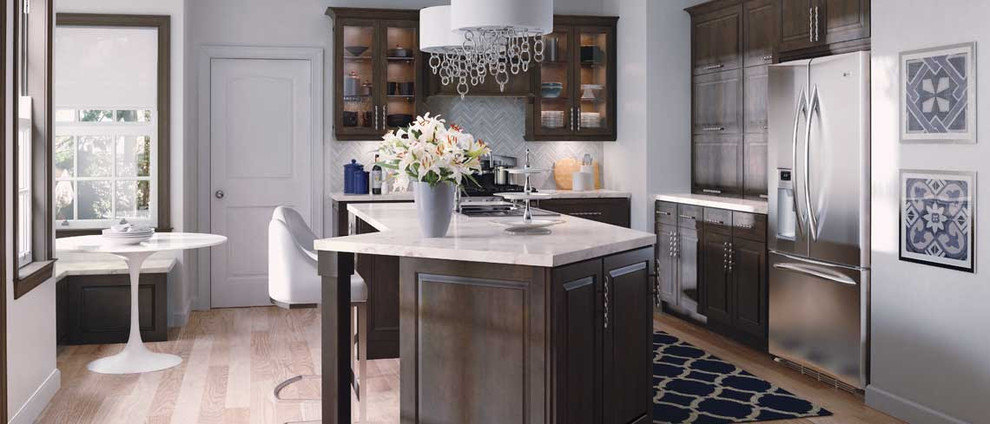 Eat-in kitchen - large traditional l-shaped light wood floor eat-in kitchen idea with glass-front cabinets, dark wood cabinets, gray backsplash, stainless steel appliances and an island
