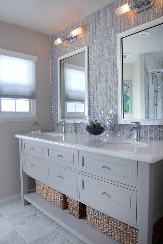 This is an example of a small beach style bathroom in San Diego with shaker cabinets, grey cabinets, an alcove tub, a shower/bathtub combo, a one-piece toilet, gray tile, glass tile, beige walls, porcelain floors, an undermount sink and engineered quartz benchtops.