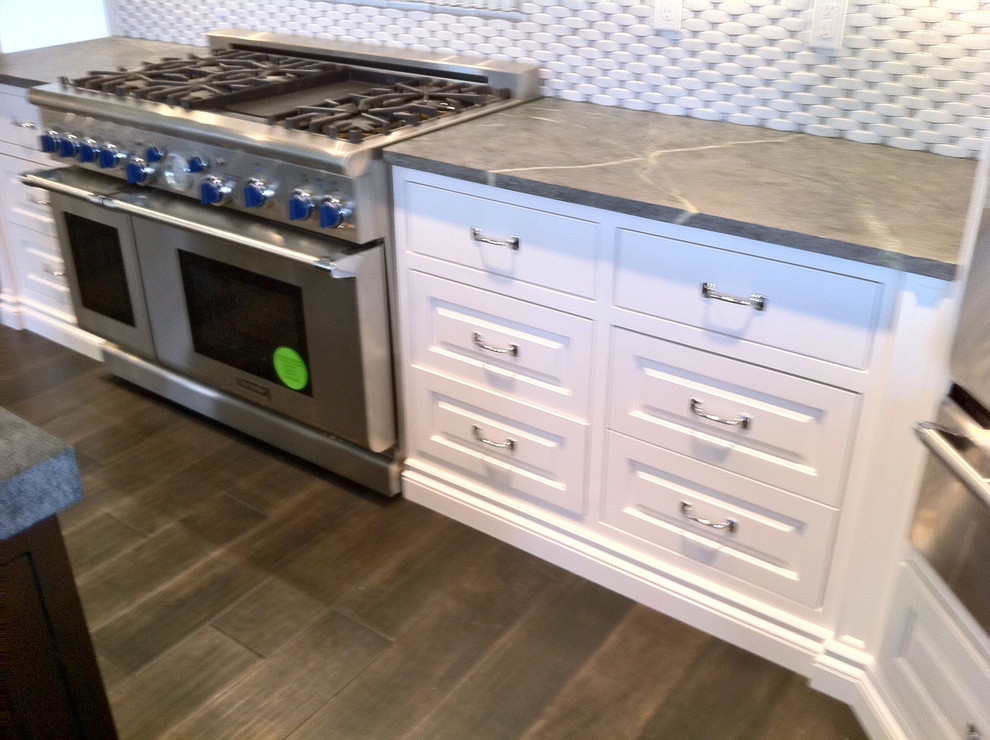 Inspiration for a large transitional u-shaped dark wood floor and brown floor open concept kitchen remodel in Miami with a farmhouse sink, shaker cabinets, white cabinets, granite countertops, multicolored backsplash, stone tile backsplash, stainless steel appliances and an island
