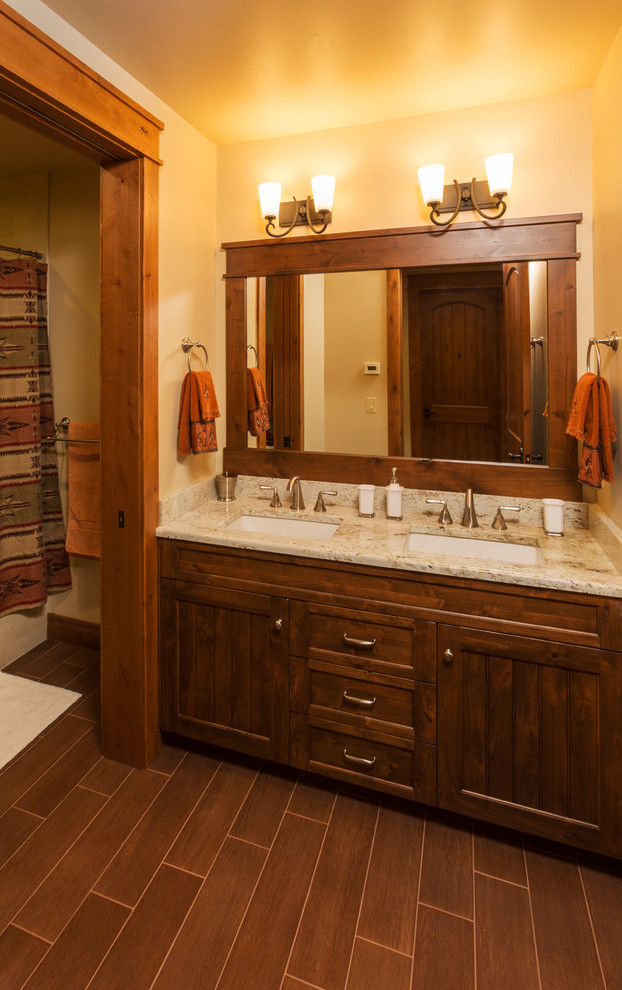 Inspiration for a mid-sized rustic porcelain tile and brown floor tub/shower combo remodel with an undermount sink, recessed-panel cabinets, granite countertops, beige walls and medium tone wood cabinets
