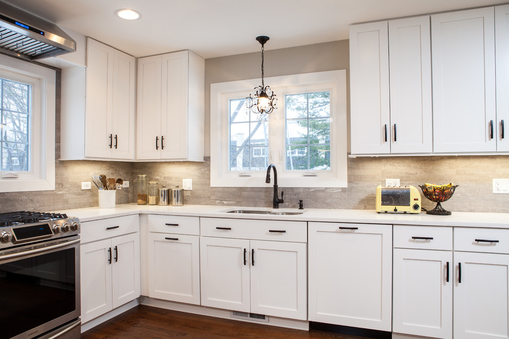 Example of a mid-sized trendy u-shaped medium tone wood floor eat-in kitchen design in Chicago with shaker cabinets, white cabinets, quartz countertops, stainless steel appliances and a peninsula