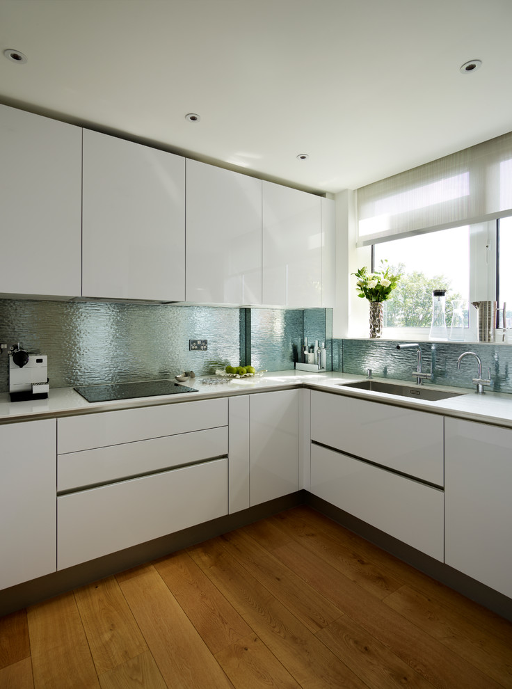 Inspiration for a contemporary kitchen in London with flat-panel cabinets, white cabinets, blue splashback, metal splashback, light hardwood floors and brown floor.