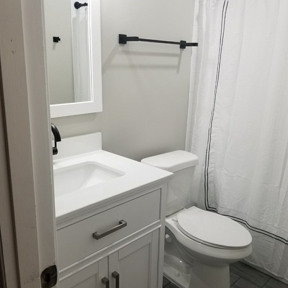 This is an example of a small transitional kids bathroom in Birmingham with flat-panel cabinets, white cabinets, a drop-in tub, a shower/bathtub combo, a two-piece toilet, white tile, subway tile, grey walls, an undermount sink, engineered quartz benchtops, a shower curtain and white benchtops.