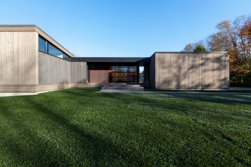 Modelo de fachada de casa gris y gris minimalista de tamaño medio de una planta con revestimiento de madera, tejado de un solo tendido, tejado de metal y tablilla