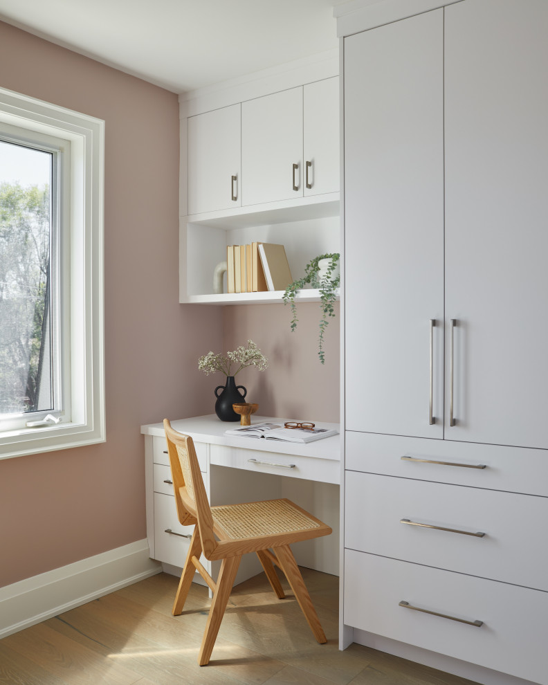 Small transitional study room in Toronto with pink walls, light hardwood floors, a built-in desk, beige floor and wood walls.