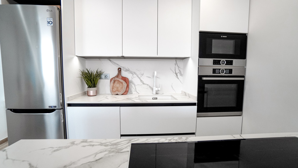 Modern inredning av ett mellanstort vit linjärt vitt kök och matrum, med en undermonterad diskho, släta luckor, vita skåp, bänkskiva i kvarts, vitt stänkskydd, rostfria vitvaror, klinkergolv i porslin, en köksö och brunt golv