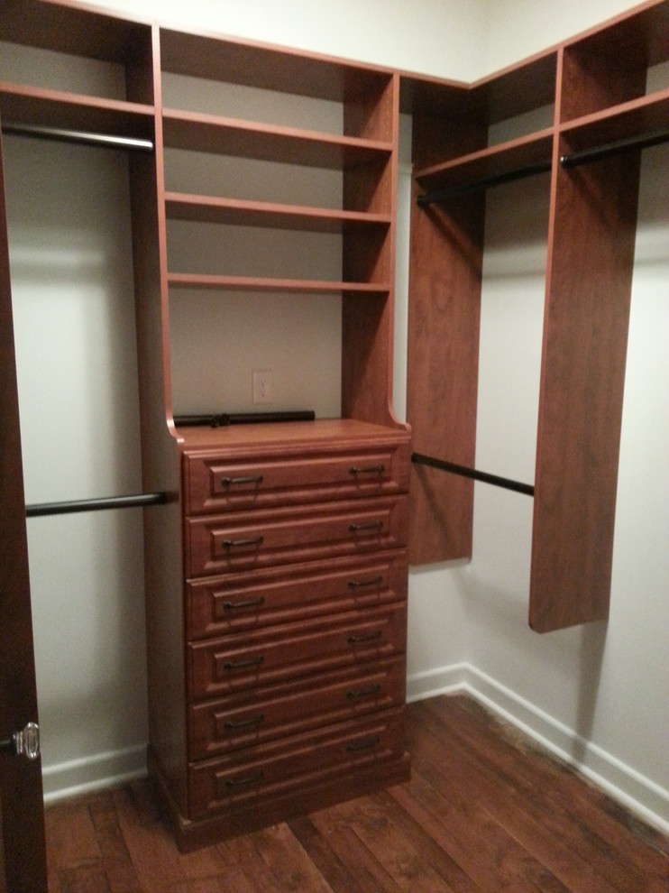 Photo of a mid-sized transitional gender-neutral walk-in wardrobe in Jacksonville with raised-panel cabinets, dark wood cabinets, dark hardwood floors and brown floor.