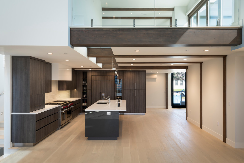 Example of a large minimalist l-shaped light wood floor open concept kitchen design in San Diego with an undermount sink, flat-panel cabinets, dark wood cabinets, quartz countertops, white backsplash, glass tile backsplash, paneled appliances, an island and white countertops