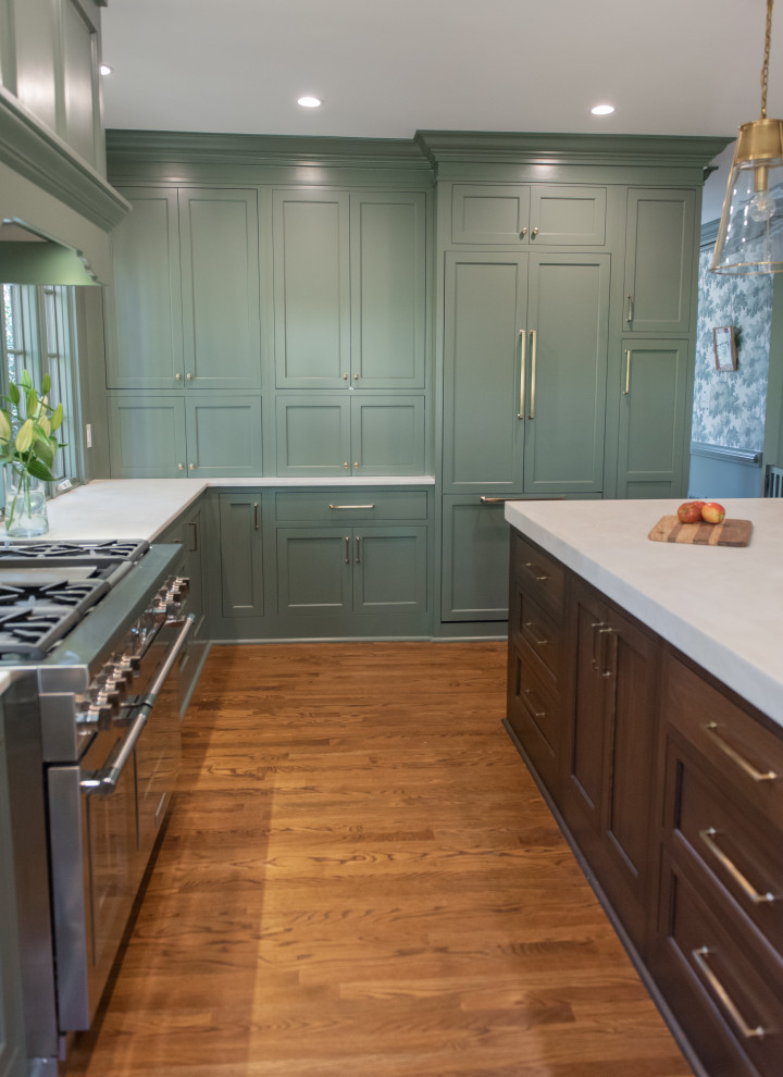 This is an example of a large bohemian u-shaped kitchen pantry in Atlanta with a belfast sink, flat-panel cabinets, green cabinets, quartz worktops, green splashback, wood splashback, integrated appliances, dark hardwood flooring, an island, brown floors and white worktops.