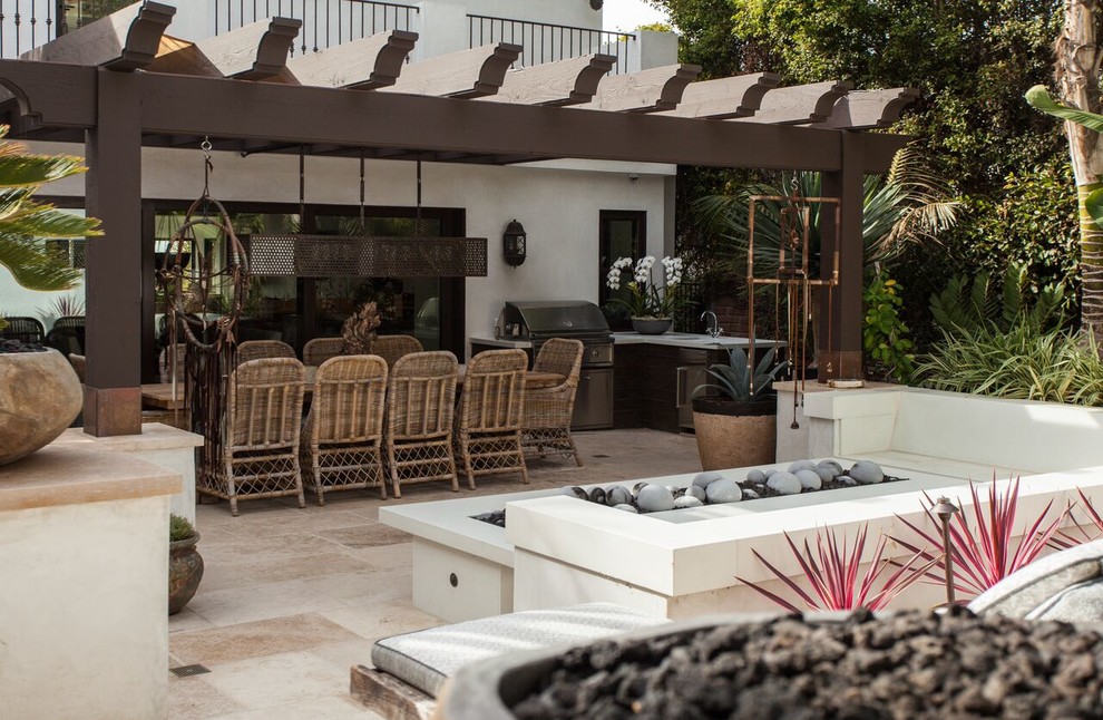 This is an example of a large mediterranean backyard patio in Orange County with a fire feature, natural stone pavers and a pergola.