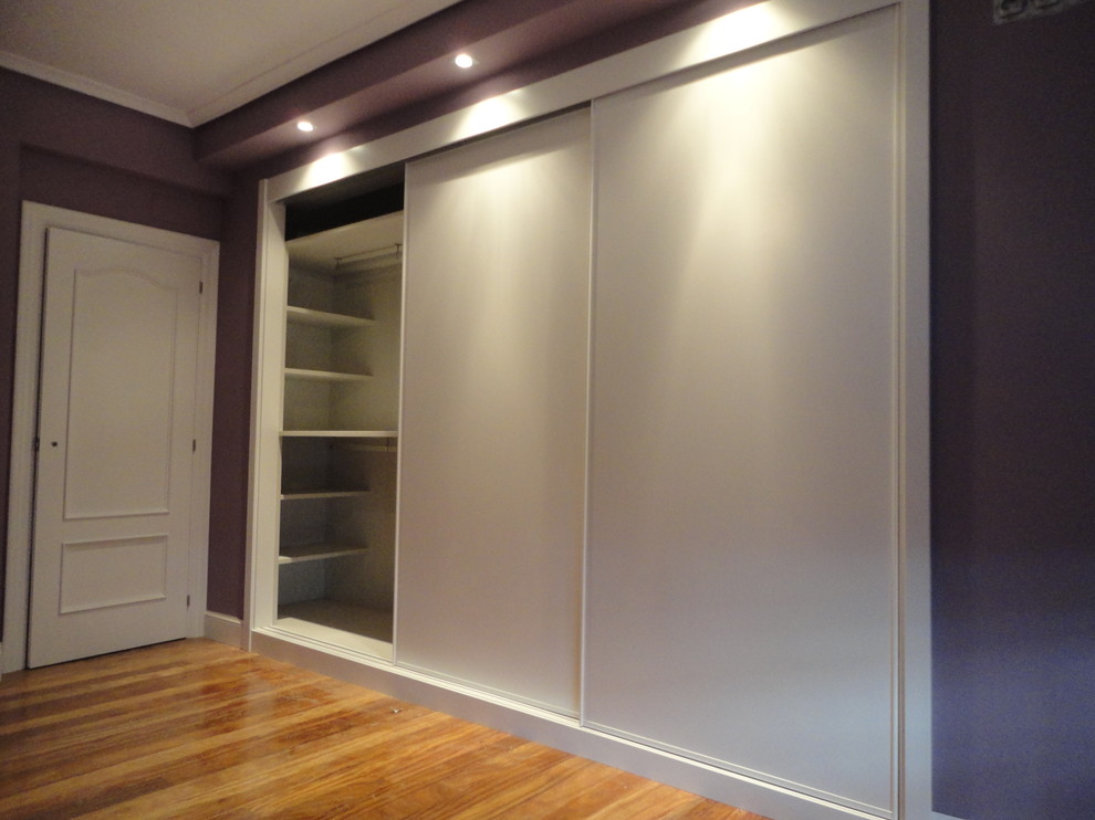 Design ideas for a mid-sized transitional gender-neutral built-in wardrobe in Other with flat-panel cabinets, white cabinets and medium hardwood floors.
