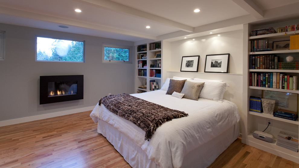 Inspiration for a large contemporary master bedroom in Vancouver with a standard fireplace, grey walls, medium hardwood floors and brown floor.