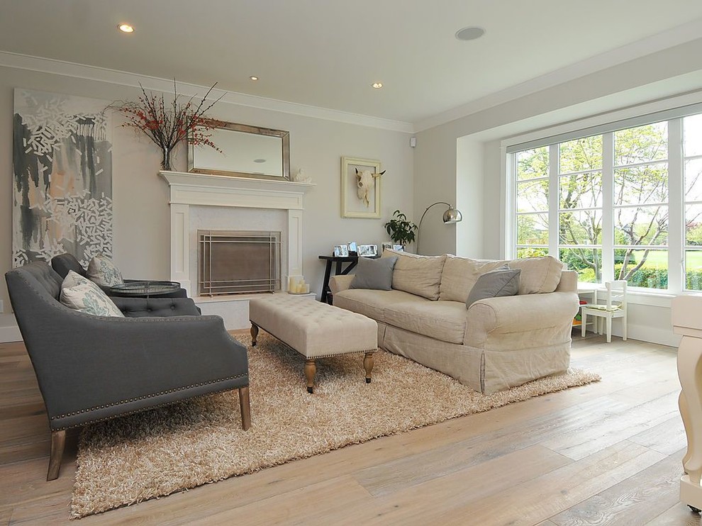 This is an example of a traditional living room in Vancouver with grey walls, light hardwood floors and a standard fireplace.