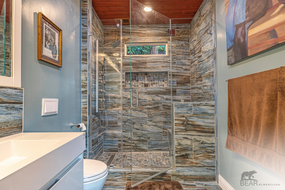 На фото: детская ванная комната среднего размера с плоскими фасадами, душем в нише, инсталляцией, синей плиткой, керамической плиткой, синими стенами, накладной раковиной, столешницей из искусственного камня, синим полом, открытым душем, белой столешницей, сиденьем для душа, подвесной тумбой и деревянным потолком