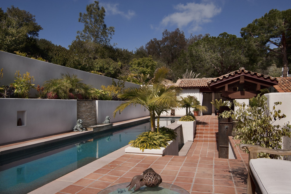 Inspiration for a large mediterranean backyard rectangular lap pool in San Diego with a water feature and tile.