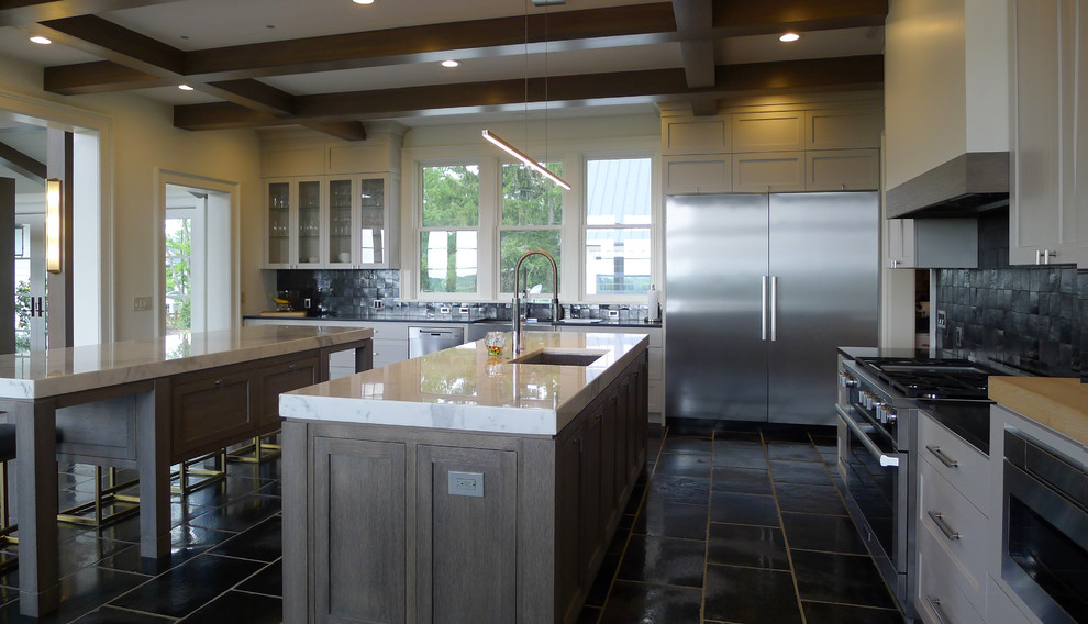Photo of an expansive modern l-shaped kitchen in Cleveland with an undermount sink, recessed-panel cabinets, marble benchtops, black splashback, mosaic tile splashback, stainless steel appliances, porcelain floors, multiple islands, black floor and white benchtop.