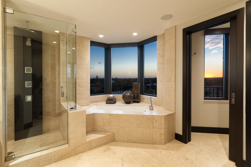 This is an example of an expansive modern master bathroom in Miami with flat-panel cabinets, black cabinets, a corner tub, an alcove shower, beige tile, marble, beige walls, marble floors, an undermount sink, limestone benchtops, beige floor, a hinged shower door and black benchtops.