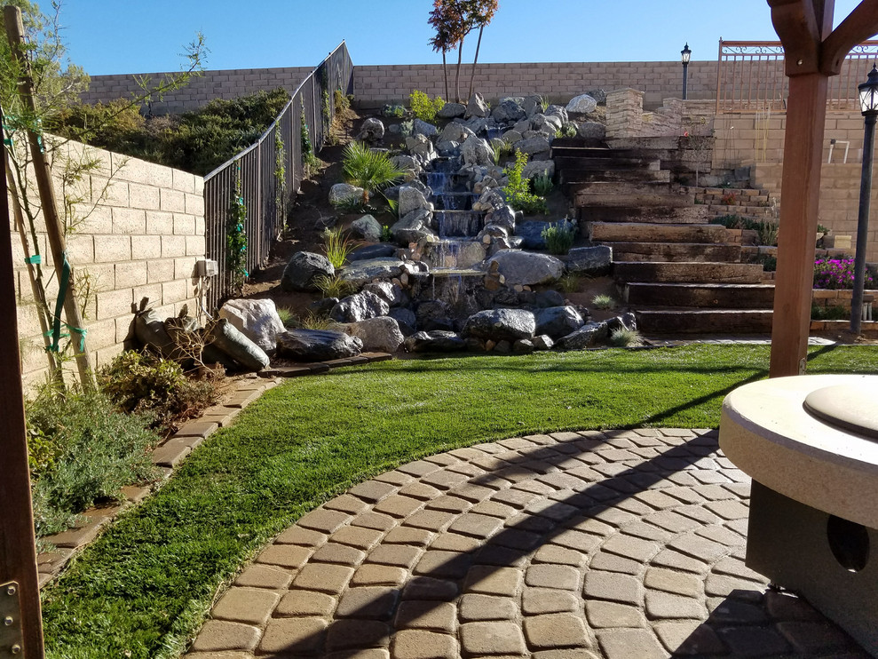 This is an example of a mid-sized transitional backyard partial sun garden in Los Angeles with with waterfall and concrete pavers.