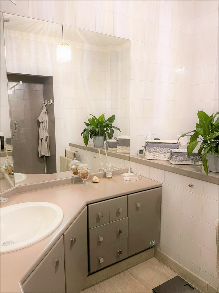 Modelo de cuarto de baño único y a medida actual pequeño con sanitario de una pieza, paredes blancas, suelo de baldosas de porcelana, lavabo sobreencimera, encimera de cuarcita, suelo gris y encimeras rosas