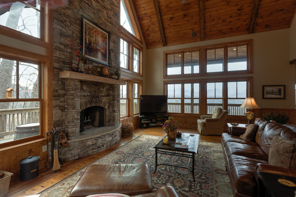 Large country loft-style family room in Charlotte with beige walls, medium hardwood floors, a standard fireplace, a stone fireplace surround and a freestanding tv.
