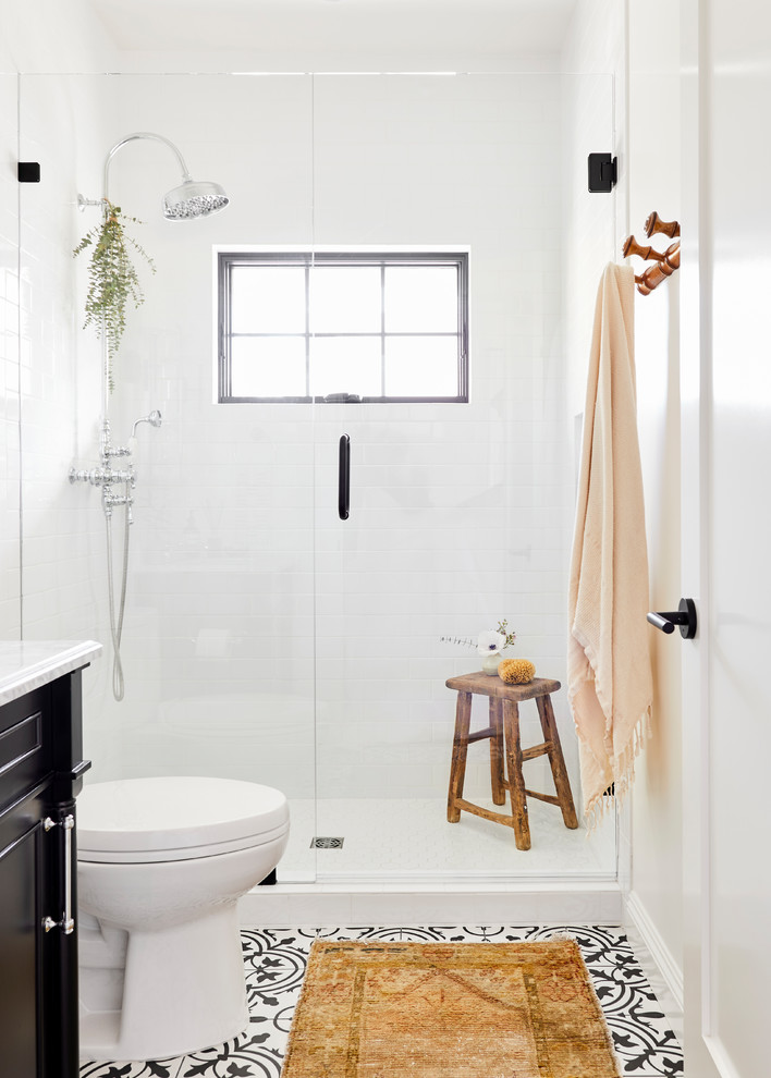 Inspiration for a medium sized mediterranean shower room bathroom in Los Angeles with freestanding cabinets, black cabinets, an alcove shower, a two-piece toilet, white tiles, ceramic tiles, white walls, cement flooring, a submerged sink, marble worktops, white floors, a hinged door and white worktops.