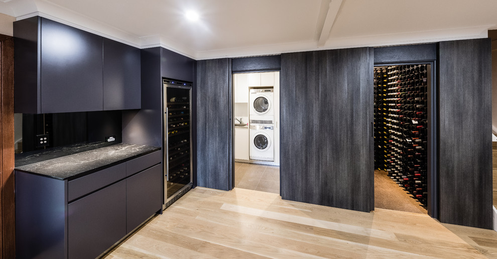 This is an example of a contemporary home bar in Sydney with flat-panel cabinets, grey cabinets, quartz benchtops, grey splashback, light hardwood floors, beige floor, grey benchtop and mirror splashback.
