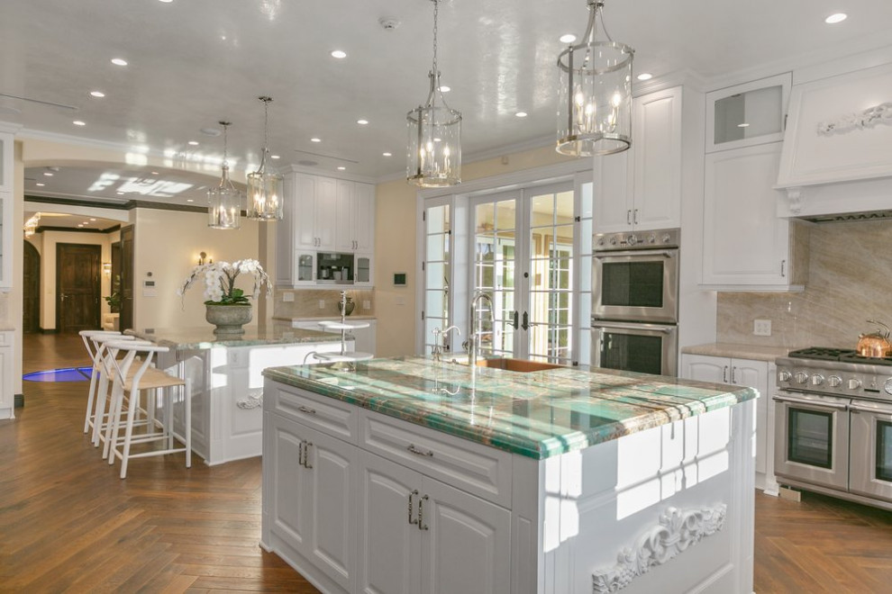 Inspiration for a large transitional u-shaped separate kitchen in Los Angeles with a farmhouse sink, shaker cabinets, white cabinets, marble benchtops, beige splashback, marble splashback, stainless steel appliances, dark hardwood floors, multiple islands, multi-coloured floor and turquoise benchtop.